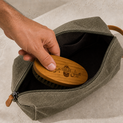 A hand packing the etched Diggn'It Bamboo Beard Brush into the Men's Travel Bag