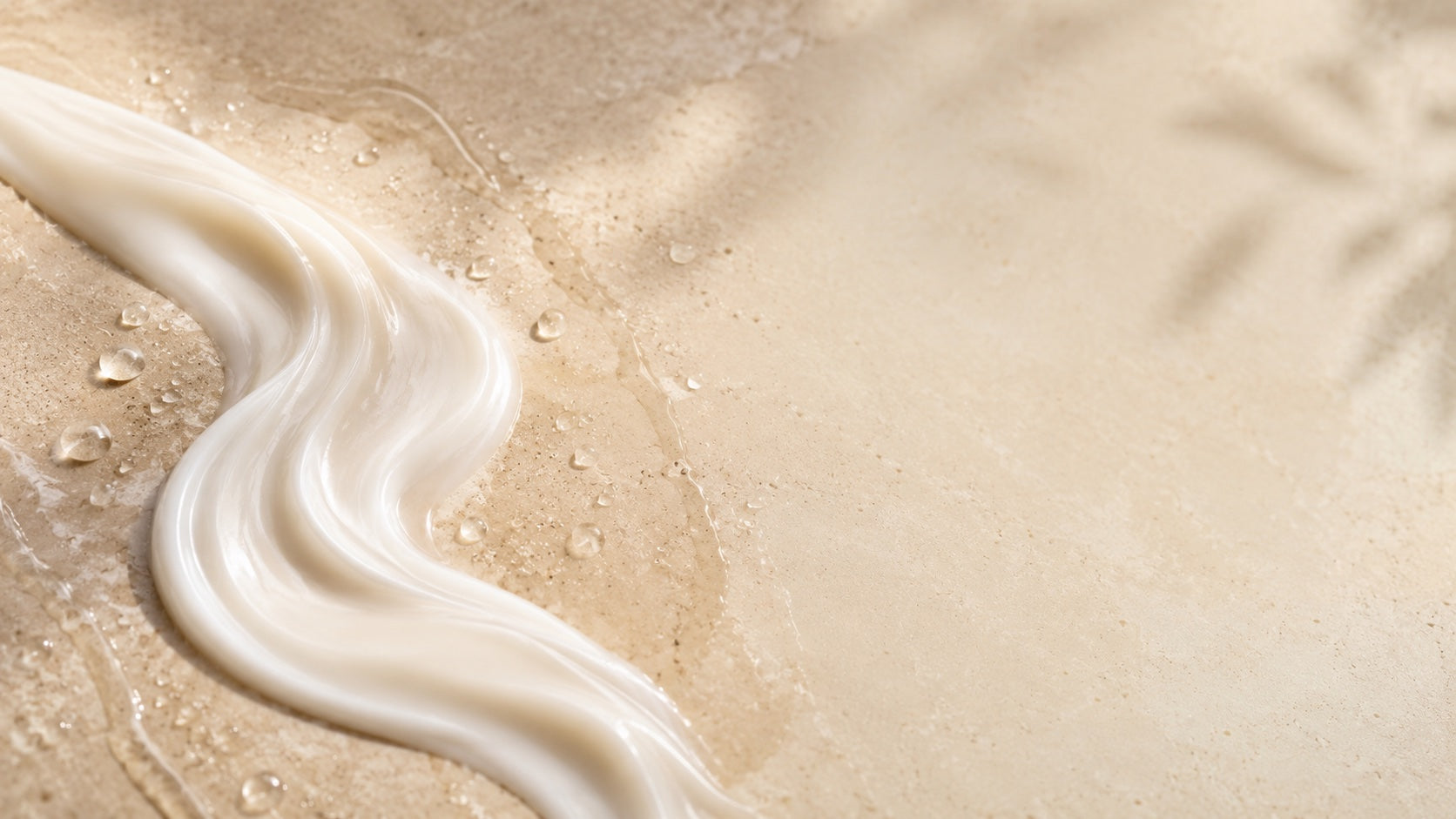 Creamy conditioner ribbon with water droplets on stone