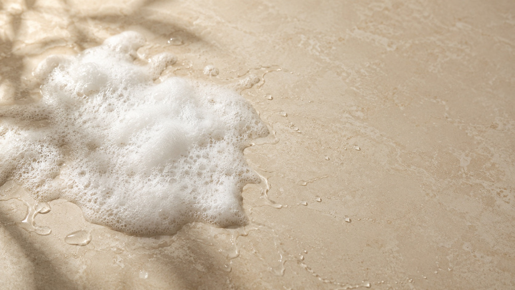 Airy lather and glossy water trails on warm stone